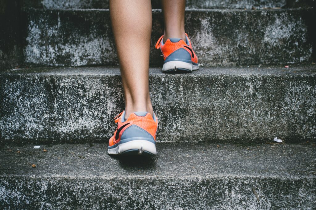 Close up of person's feet with running shoes climbing cement stairs