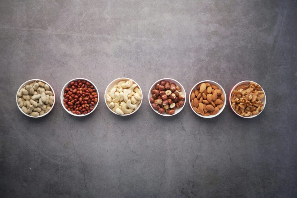 dried beans, nuts, and seeds in small white bowls on a gray surface